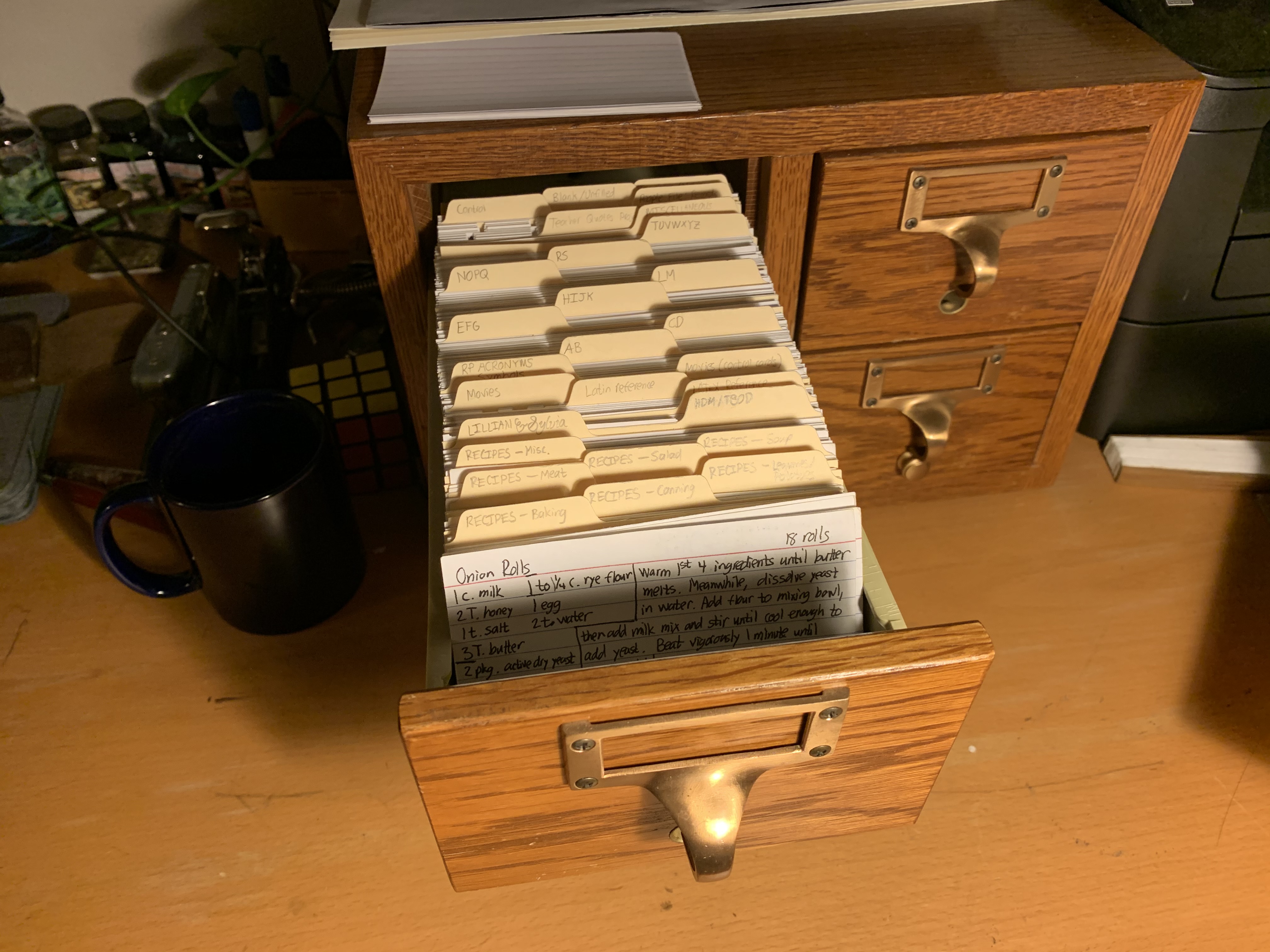 A four-drawer card catalog cabinet, two by two, with one drawer pulled out most of the way to show a long row of three-by-five cards with manila dividers.